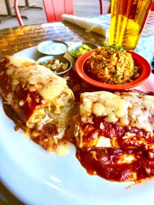 Delicious chicken burrito with hot sauce and melted cheese, a flavorful Mexican cuisine specialty at Las Cruces Tex Mex in Metairie.