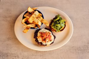 An open-faced black bean burger with cheese accompanied by seasoned fries - Mexican restaurant metairie