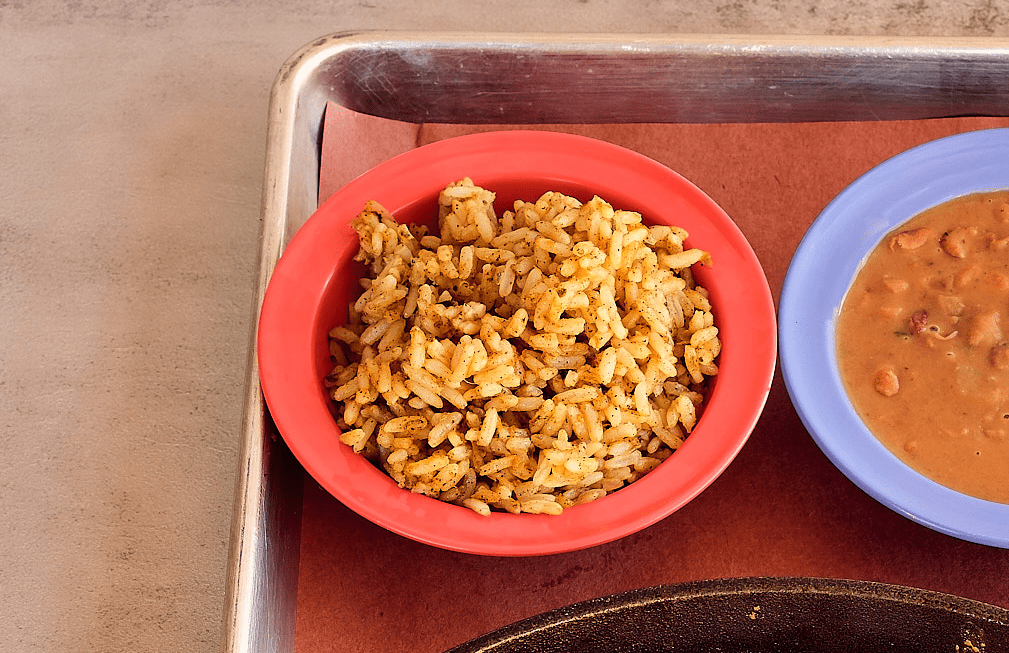 Brightly colored bowls featuring seasoned rice and creamy beans, classic sides from a Mexican restaurant in Metairie